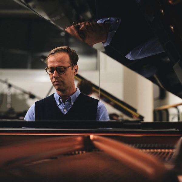 Pianist Michael Scales seated at a piano in front of city skyline