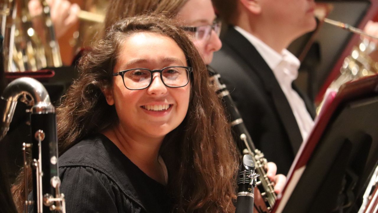 A smiling clarinet player in the woodwind section of a concert band