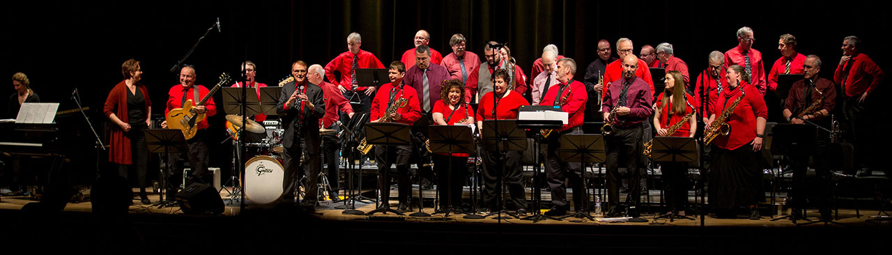 KU alumni jazz band performing on stage in red shirts and black pants 