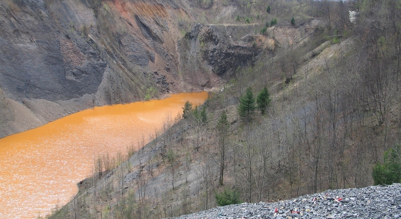 River flowing through a forested mountainside, colored orange by the setting sun