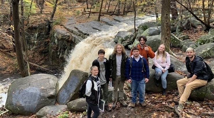 KU Geology students smiling in a group in front of a waterfall