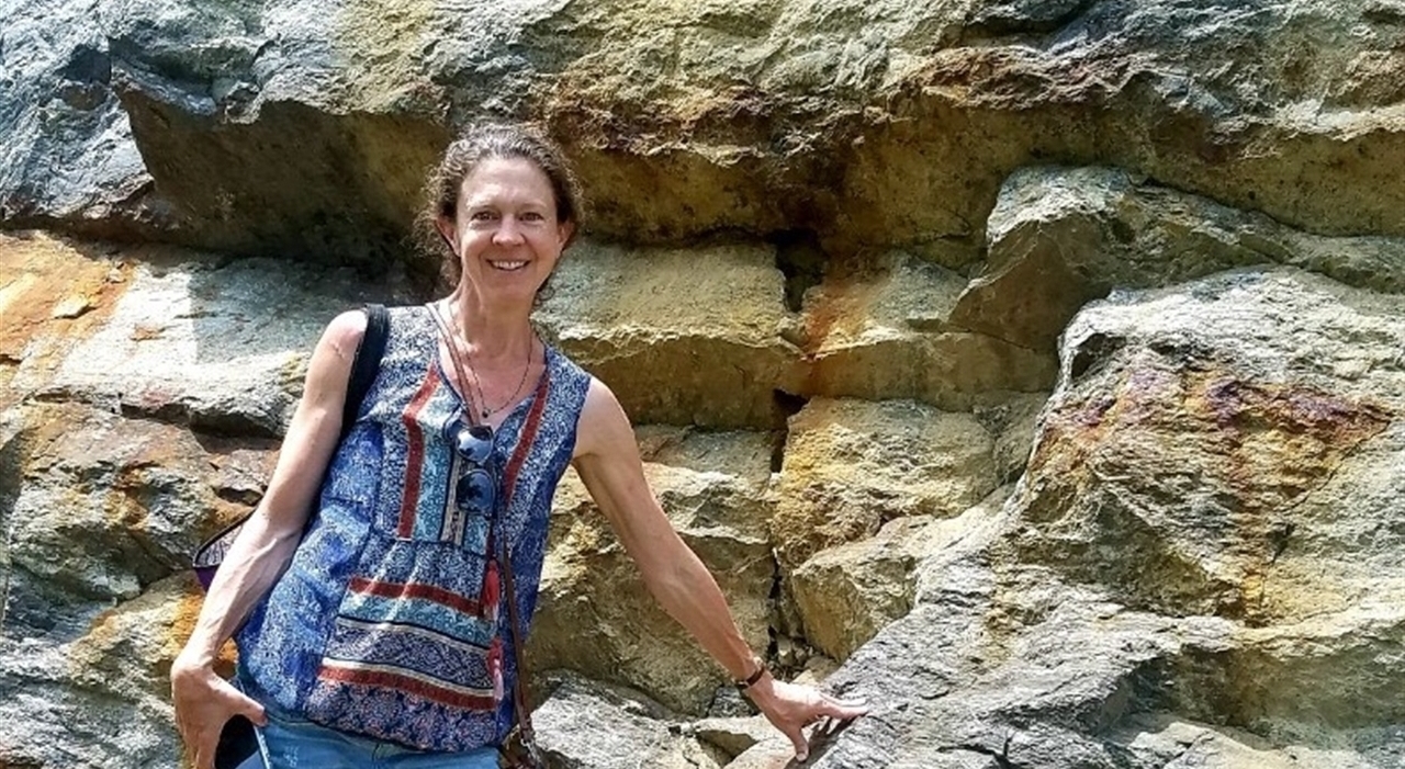 Woman standing in front of large cliffside 