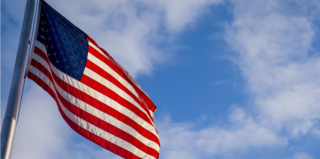Closeup of the American flag, flying in the air on a steel pole 