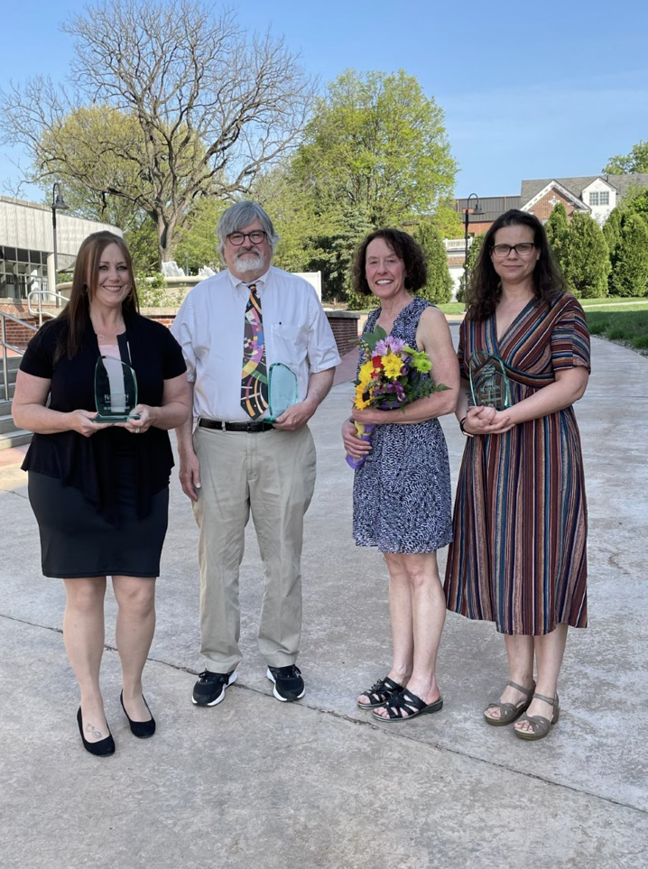 Under blue skies faculty mentorships award recipients, Dr. Johnson, Dr. Parson, and Dr. Clemens pose with their awards with Dr. Kutch, committee chairperson.