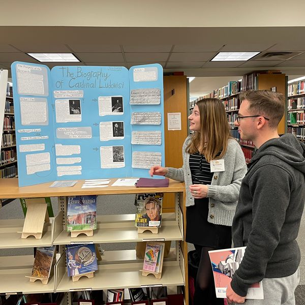 Students looking at blue poster for KU Inspires