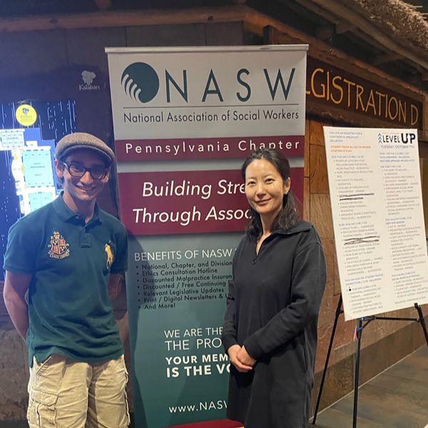 Student and Teacher standing by a Social Work Sign