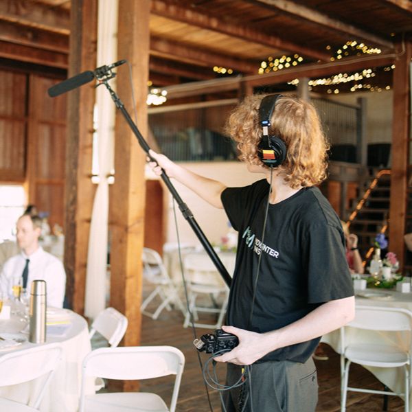 Student holding a microphone filming in what appears to be a wedding venue