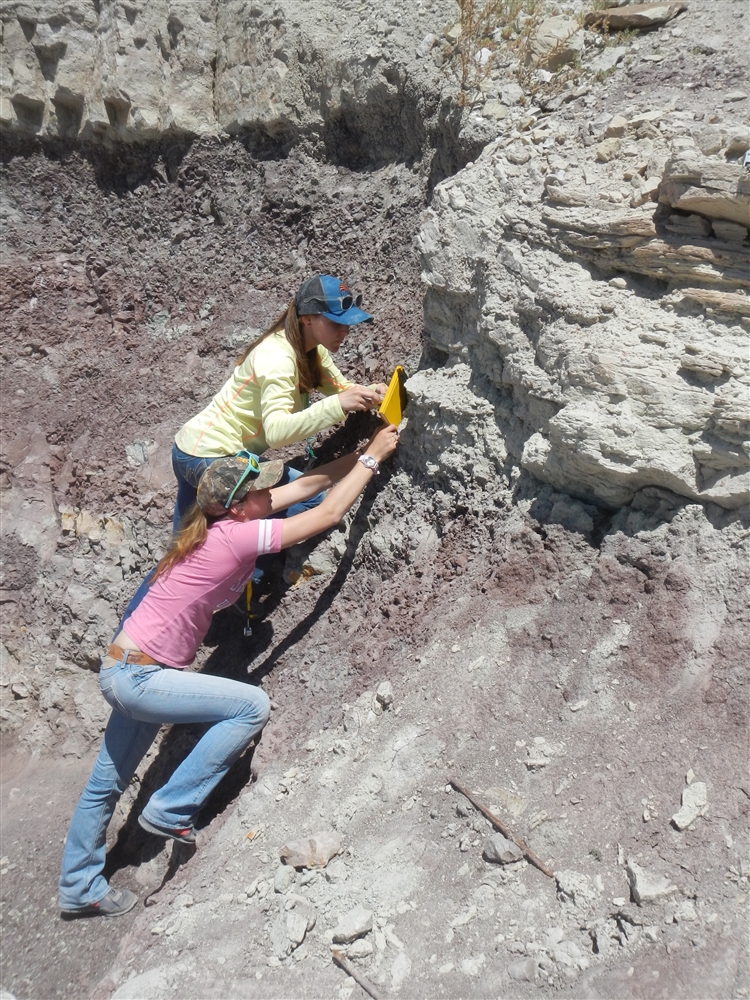 two students climbing up a hill with rocks