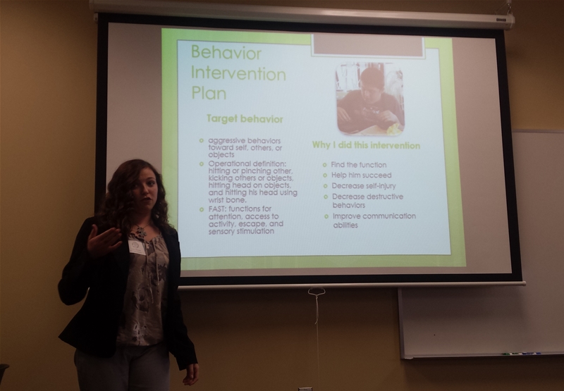 Female student presenting a slide with the title "Behavior Intervention Plan." 