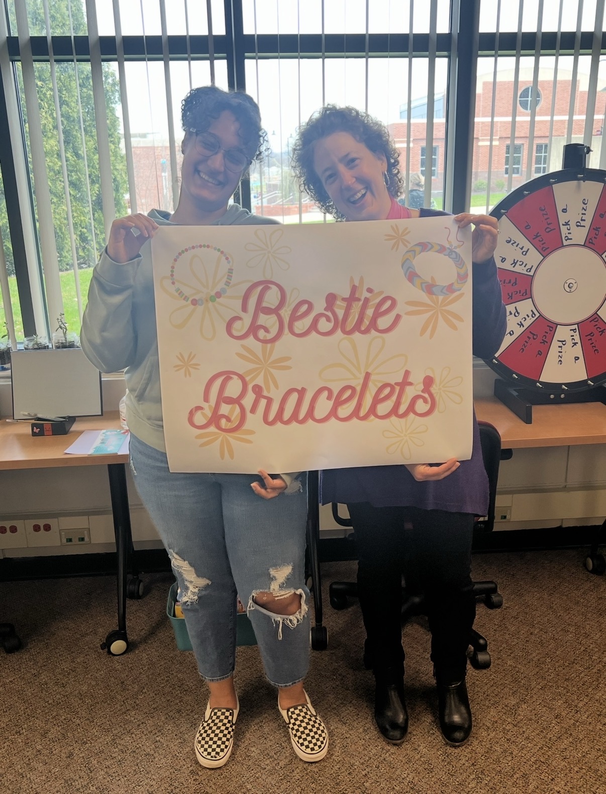 TRIO Director and Student smiling holding a sign for bestie bracelets