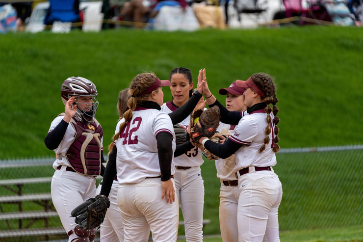 Members of the Kutztown University softball team meet on the mound during a game. 