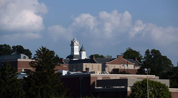 Blue skies and white fluffy clouds are the backdrop looking towards South Campus and Old Main Clock Tower. 