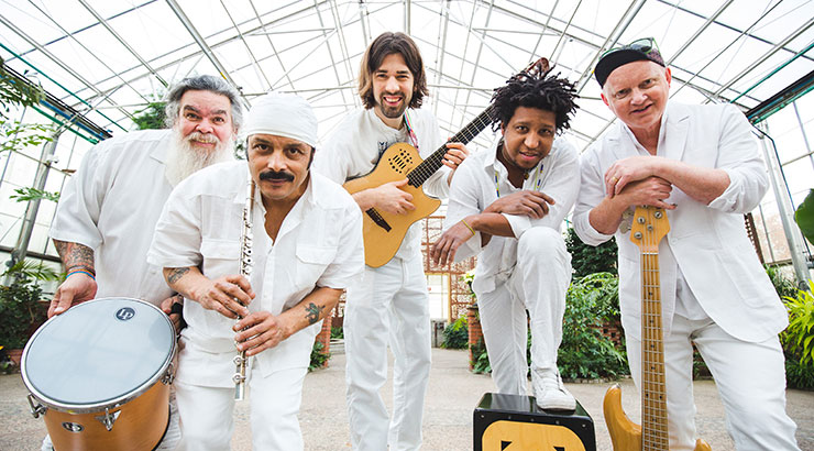 Photo of five "DeTierra Caliente" band members in white cotton outfits with their instruments.