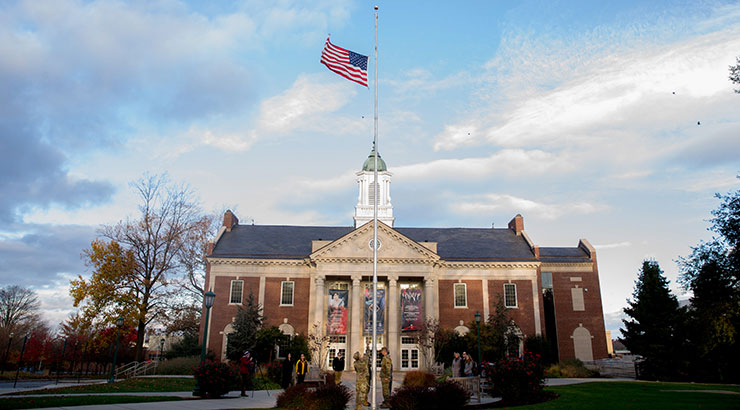 Flag on pole with Schaeffer Auditorium in background.