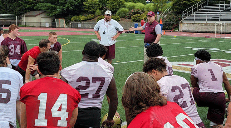 Photo of President Hawkinson with the football team during practice Friday, Aug. 20.