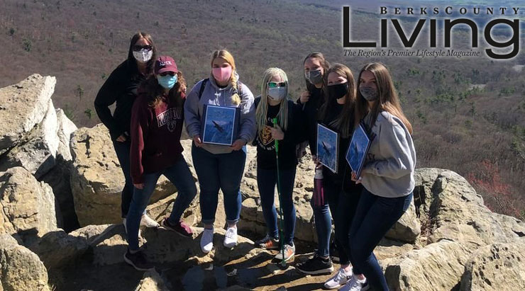 Seven KU students in the visual impairment program pose for a picture on the rocks overlooking the valley at Hawk Mountain Sanctuary. 