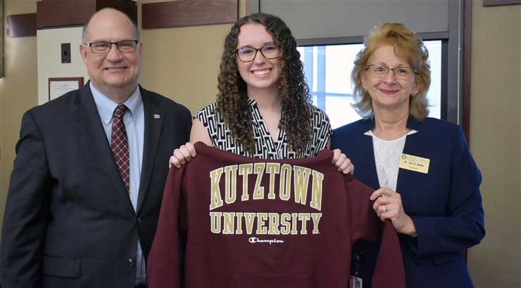 Hawkinson, LCCC student and LCCC President posing for picture, holding Kutztown University maroon sweatshirt.