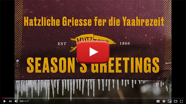 Image links to YouTube video of the Hawkinsons' holiday greeting. Icicles on a maroon flag with the words "Hatzliche Griesse fer die Yaahrezeit" on the first line; Est. Kutztown 