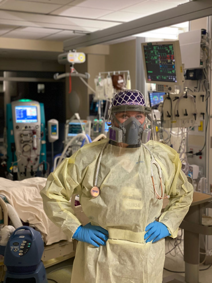 Morgan Staley stands for photo in operating room dressed in standard surgical attire and additional PPE face shield and respiratory mask.