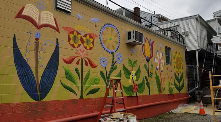 Colorful mural of various floral and industrial elements, painted on a cinder block wall of business in downtown Kutztown.