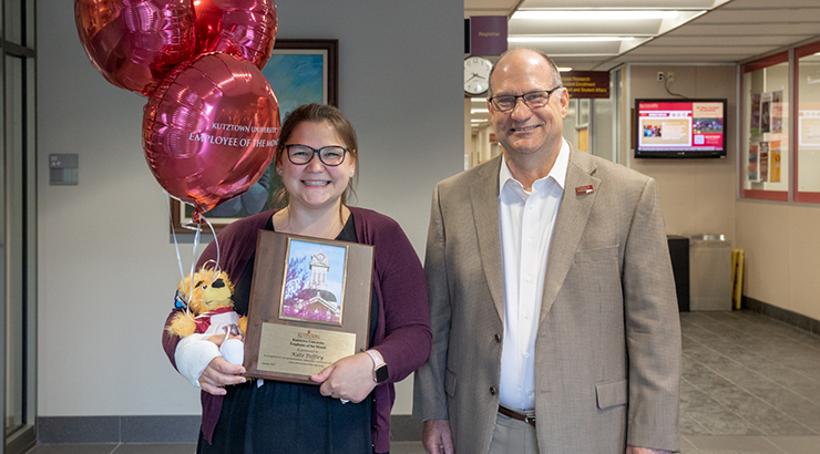 Photo of Kate Peffley (left) holding balloons, stuffed Avalanche, and Employee of the Month plaque with Dr. Hawkinson (right).