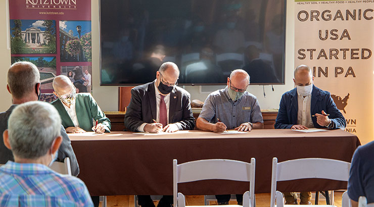 Photo of leaders from Kutztown University and Rodale Institute sitting at a table signing a research agreement.