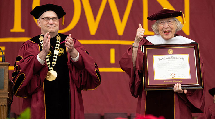 Nancy Jean Stump Sieger holds honorary doctorate as President Hawkinson applauds.