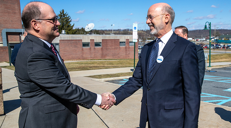 Governor Wolf (right) and Dr. Hawkinson (left) shaking hands outside of a KU building 