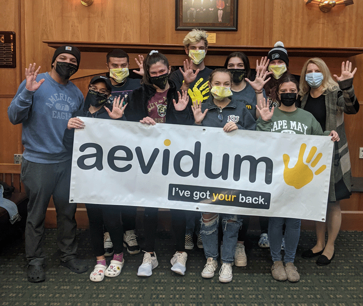 Photo of a group of students holding a sign for Aevidum training at Kutztown University.