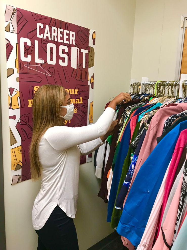 Student shops at the Career Closet. A poster with the words Career Closet is hanging on the wall behind her. 