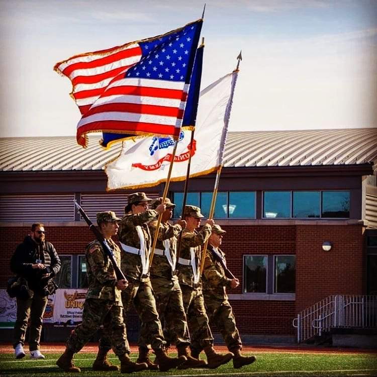 ROTC students marching on KU's football field, carrying the U.S. flag and the PA flag.