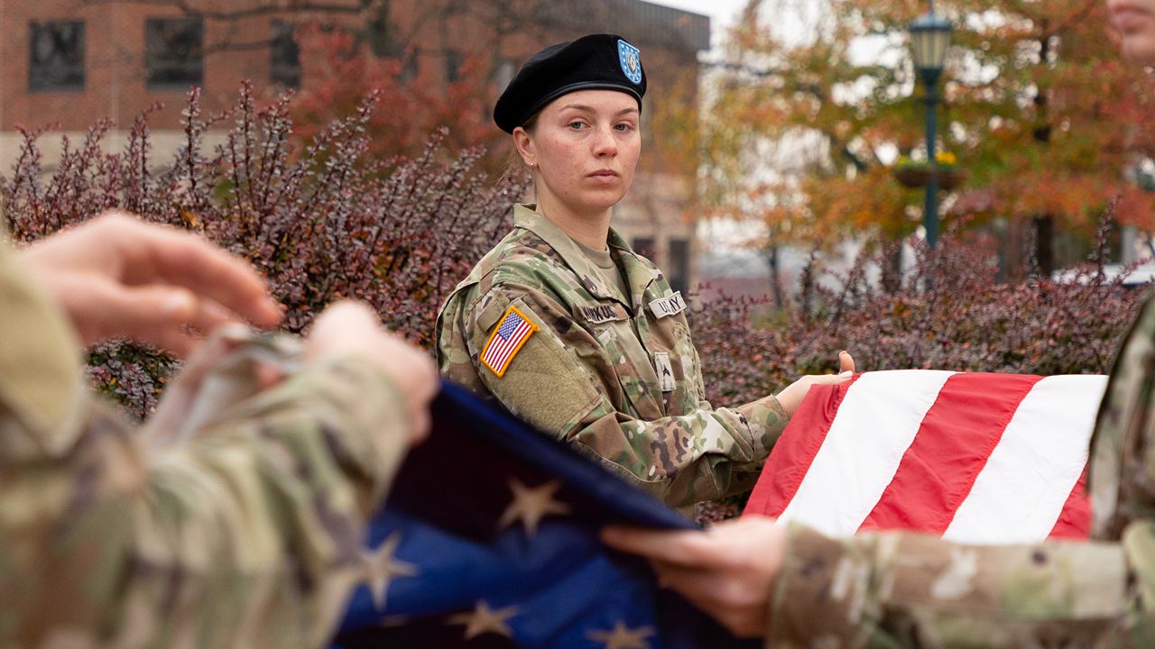 ROTC students marching with their rucksacks on a road. A quote is in the picture that reads, "we are what we repeatedly do. Excellence, then, is not an act, but a habit." Aristotle