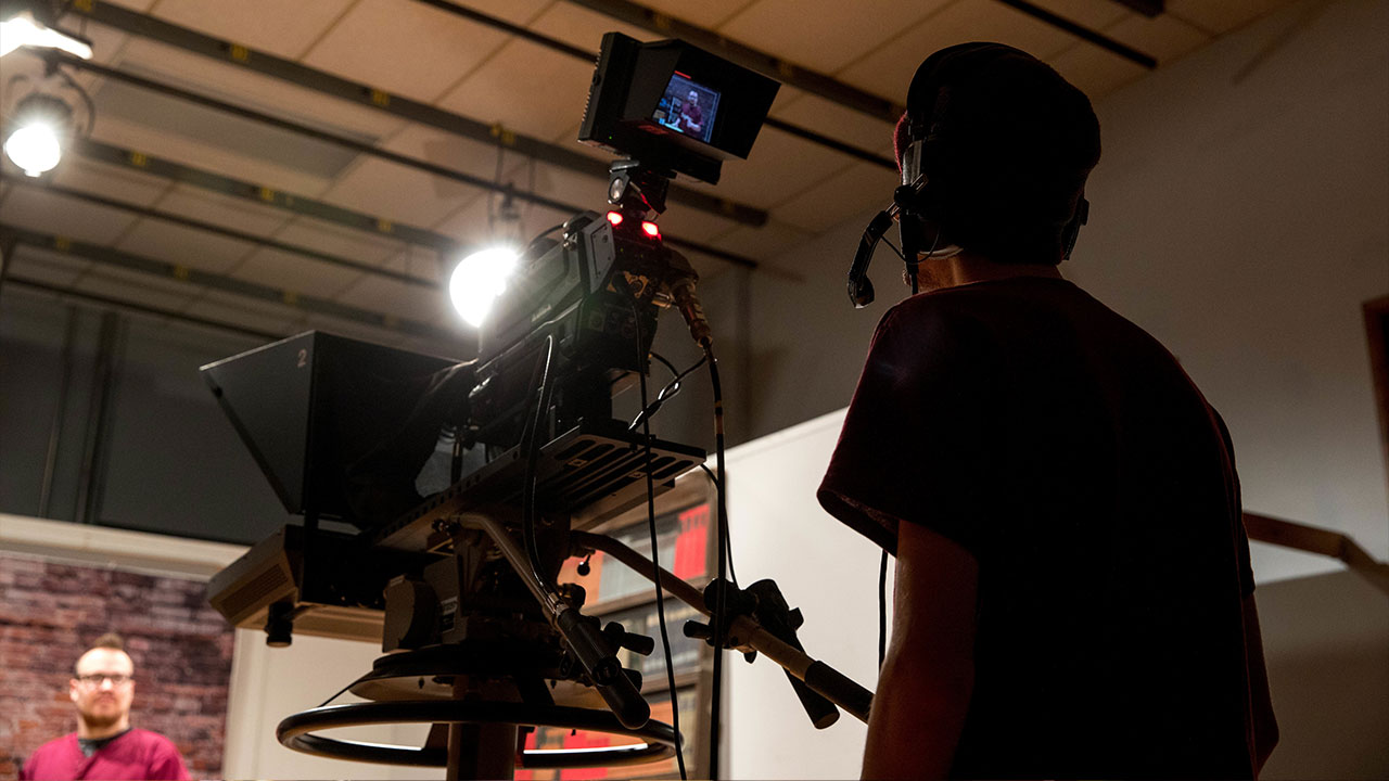 Student wearing a headset and shooting with film equipment in a studio
