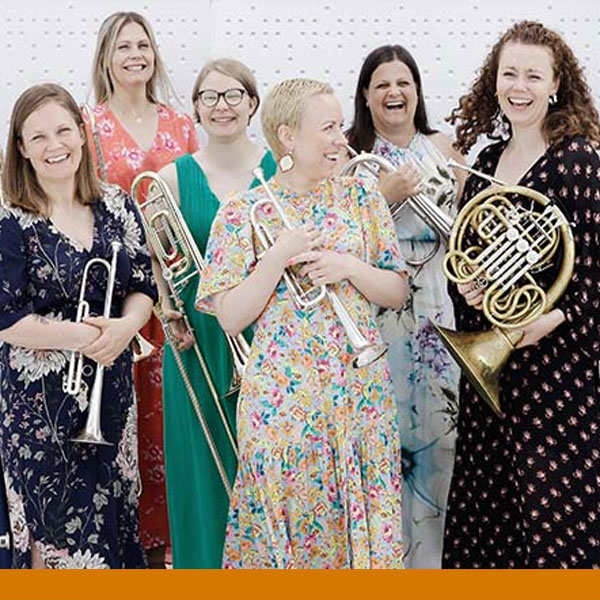 A group of female musicians hold various brass instruments.