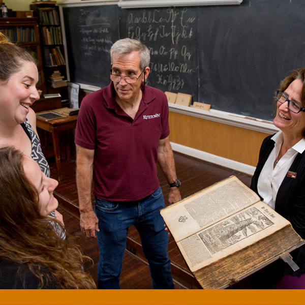 a photo of a group of people standing and looking at a heritage book