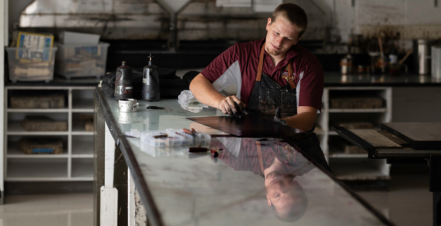 Male student working on a print in the art studio
