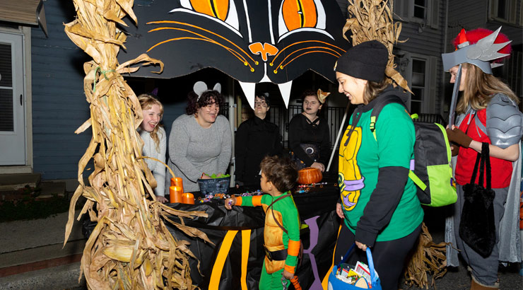 students dressed in halloween costumes host trick or treaters on Main Street in downtown Kutztown.