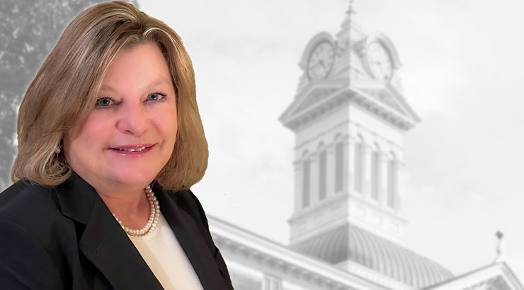 Headshot of Lori Lentz with a black-and-white photo of the Old Main clock tower in the background 