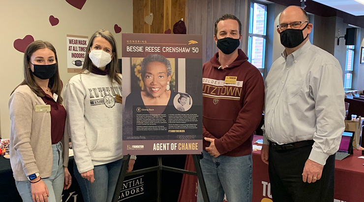 four masked participants, students and faculty, standing on either side of a headshot poster of Bessie Reese Chainsaw, agent of change 