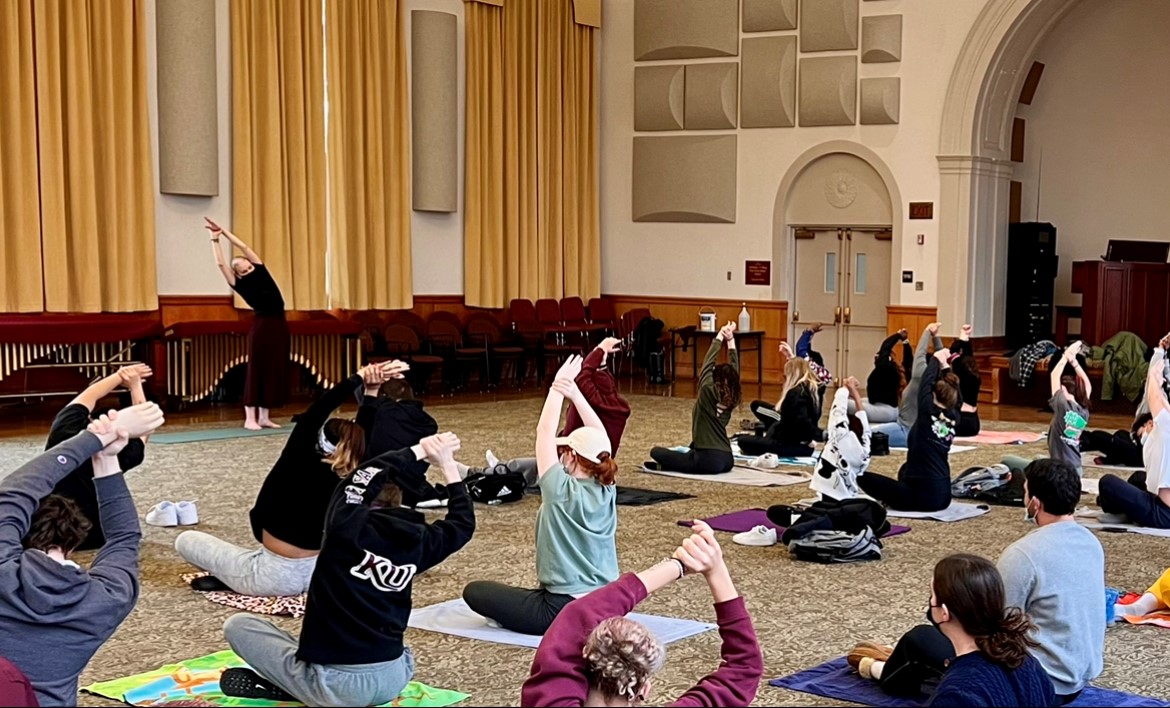 Full yoga class in Old Main, with participants in the middle of stretching 