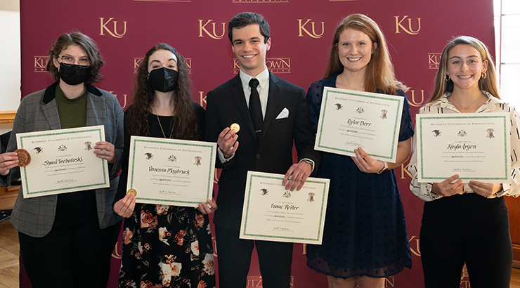 Five KU students standing in a line, holding up their Chambliss Student Academic Achievement Awards and smiling 