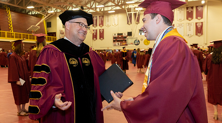 President Hawkins congratulating student at commencement 