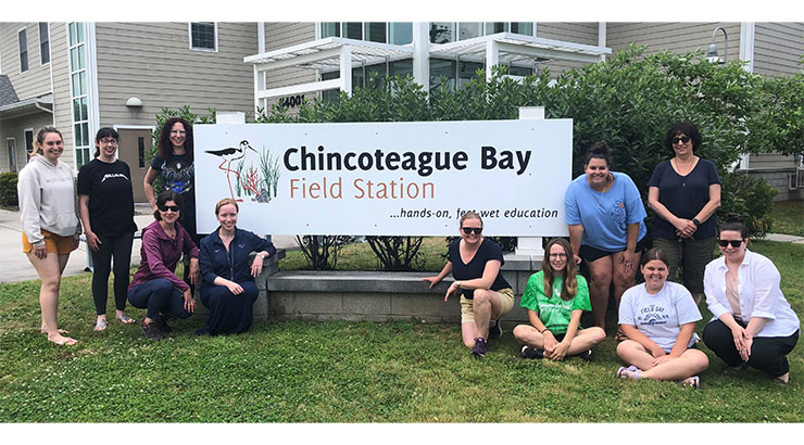 students and faculty posing in front of the Chincoteague Bay Field Station sign