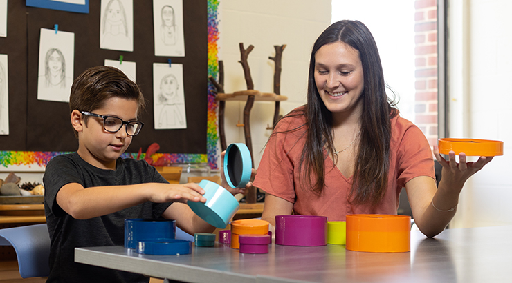 Student teacher with student sitting at a table with manipulatives