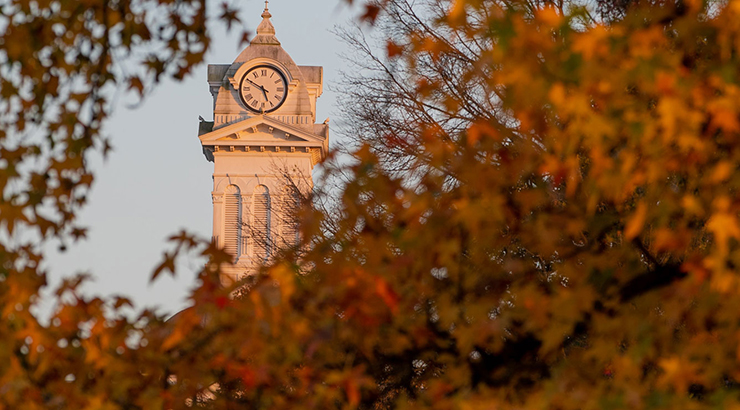 view of Old Main Clock tower through tree with fall leaves