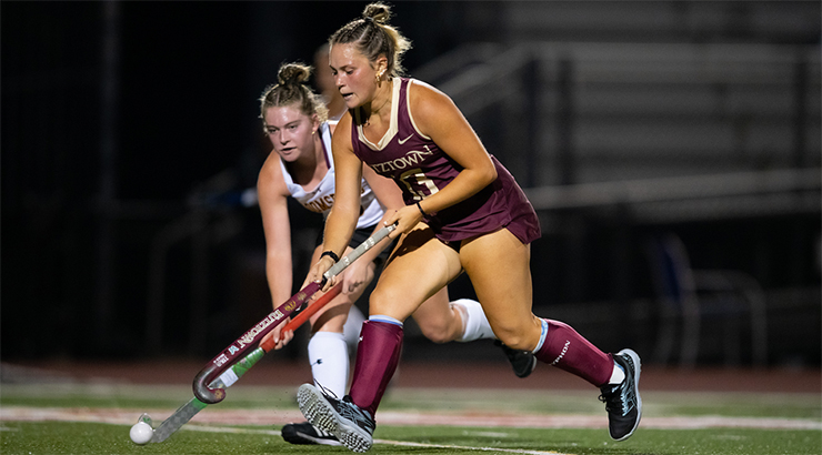 Two field hockey females on the field playing