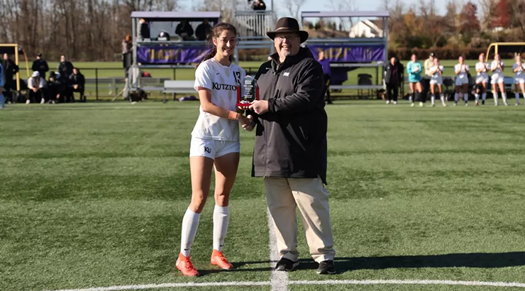 student receiving award on soccer field