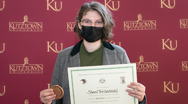 Shani Trebatoski wearing a mask and holding her Chambliss Academic Achievement copper medal 