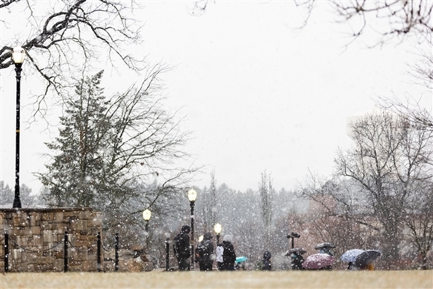 Photo of people walking in a snow shower Alumni Plaza