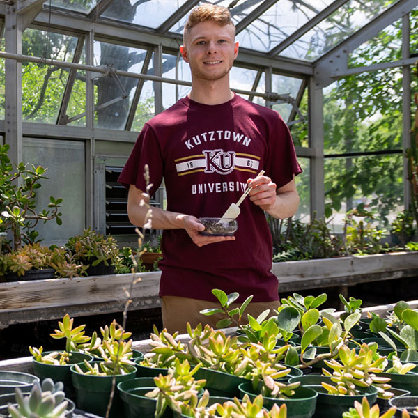 Environmental Science Major Patrick works on an experiment in the greenhouse.